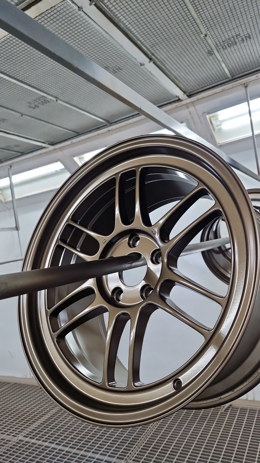 Restored bronze alloy wheel hanging in our spray booth